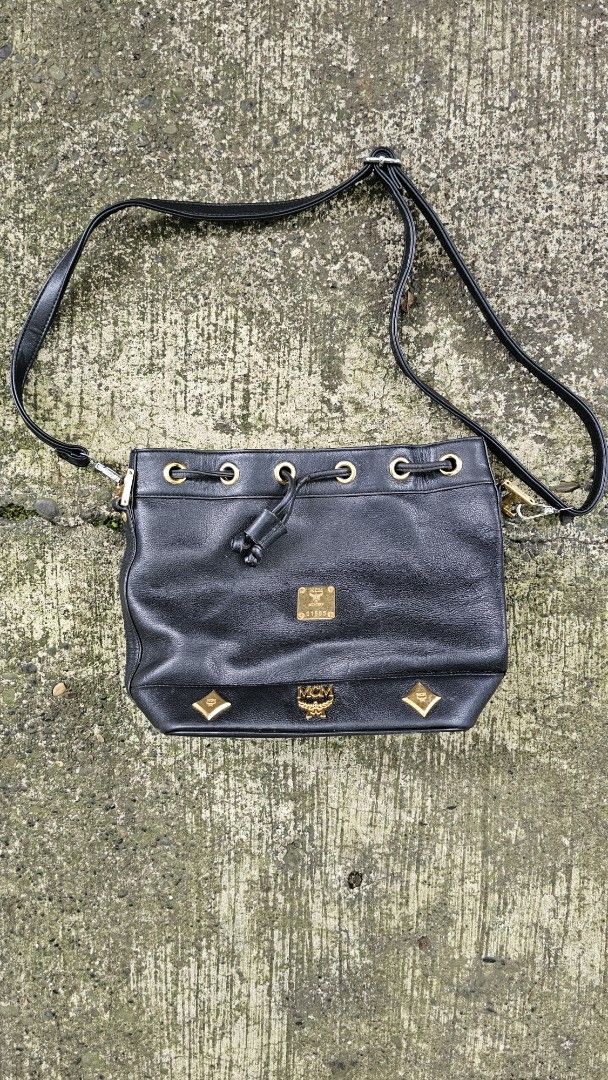 MCM Black Shoulder Bag (Category: Luxury Bags & Wallets) located in Kibawe. Submitted by Thrift_ni_Babac (Listing ID 1411185493, Image 1). Description: - Authentic MCM shoulder bag - Black with gold-tone hardware - Drawstring and zip closures - Shoulder strap - Interior MCM logo - Exterior with minor wear and tear - Gold-tone MCM logo on front - Unique design with gold accents Issue: Please refer to last 3 photos.