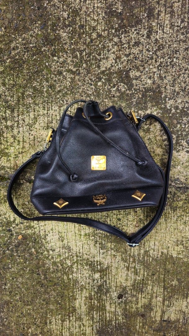 MCM Black Shoulder Bag (Category: Luxury Bags & Wallets) located in Kibawe. Submitted by Thrift_ni_Babac (Listing ID 1411185493, Image 3). Description: - Authentic MCM shoulder bag - Black with gold-tone hardware - Drawstring and zip closures - Shoulder strap - Interior MCM logo - Exterior with minor wear and tear - Gold-tone MCM logo on front - Unique design with gold accents Issue: Please refer to last 3 photos.