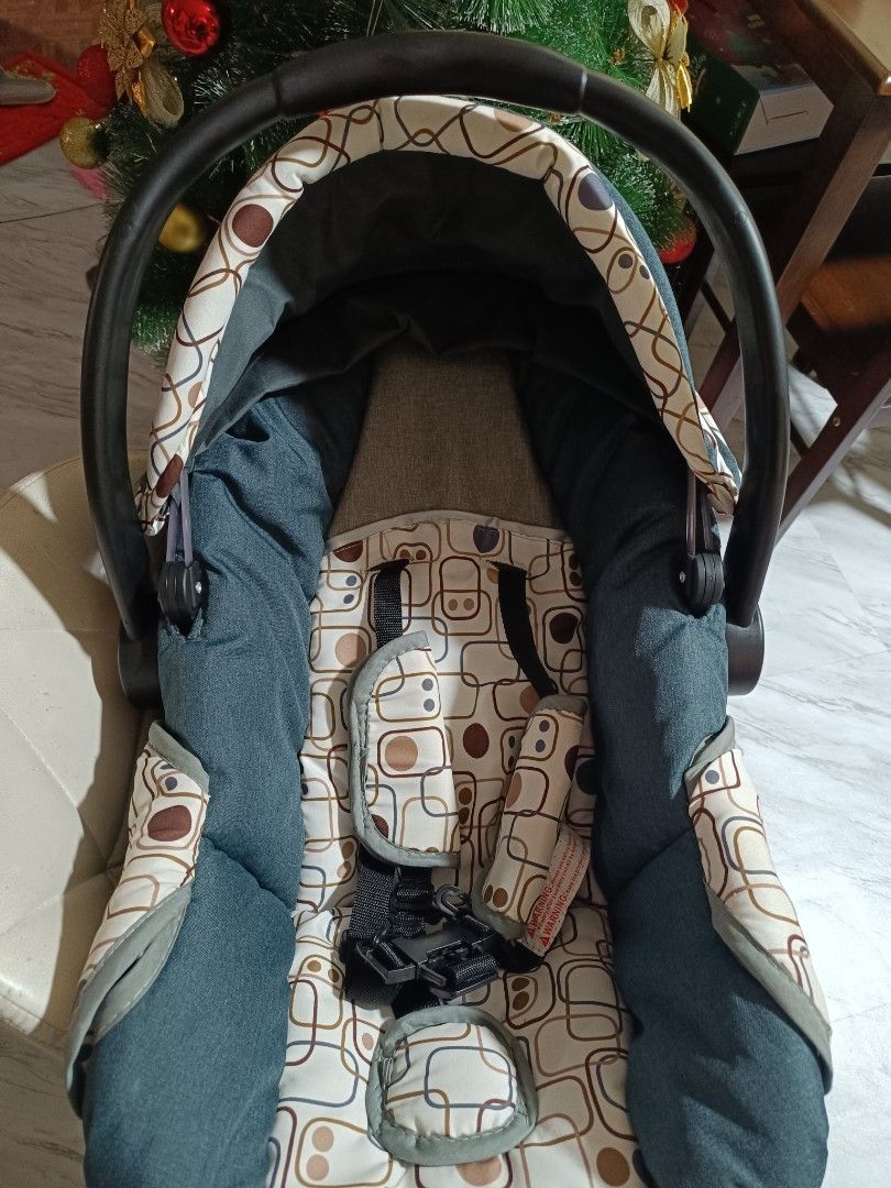 Baby Car Seat (Category: Car Seats) located in Makati City. Submitted by billyun (Listing ID 1411303556, Image 3). Description: - Stylish baby car seat - Almost new - Dark blue and beige patterned fabric - Includes a carrying handle - Features a sunshade - Equipped with a safety harness.