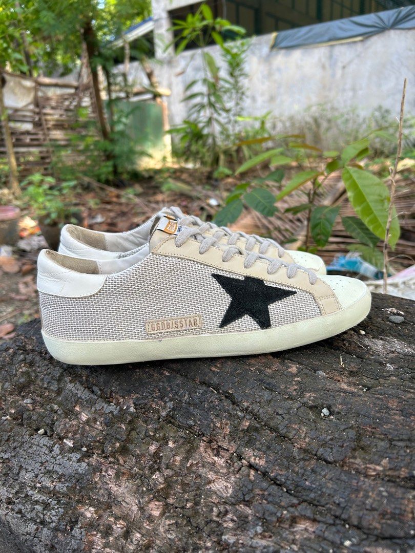 Golden Goose Superstar Sneakers (Category: Sneakers) located in Iloilo. Submitted by resellmpg (Listing ID 1411333202, Image 1). Description: Golden Goose Superstar sneakers in beige and black. Features a mesh upper with a leather star detail on the side. The sneakers have a lace-up closure and a rubber sole. The brand name is visible on the side of the shoe. The sole is a light brown color..