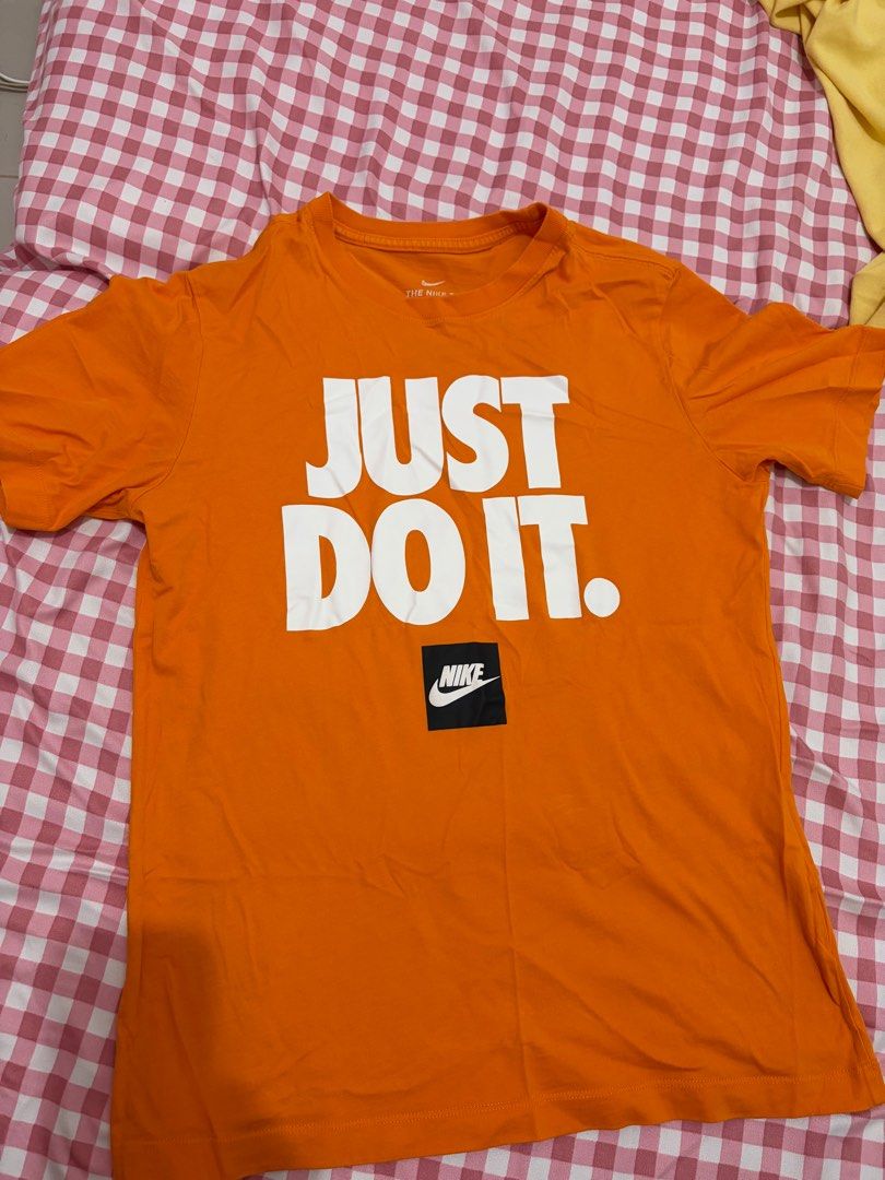 Nike Just Do It Tee - Orange (Category: Tshirts & Polo Shirts ) located in Mandaluyong City. Submitted by getbounced (Listing ID 1411329927, Image 1). Description: Orange Nike t-shirt featuring the iconic "JUST DO IT" slogan. The shirt has a small Nike logo on the front. It is a size S. Made in China. The tag also shows the style code BV7663-873. The shirt's measurements are approximately 25 inches in length and 20 inches in width..