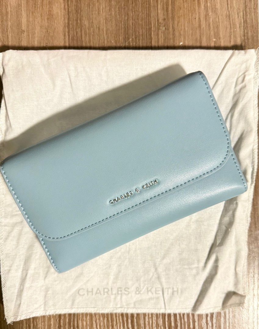Charles & Keith Front Flap Long Wallet - Slate Blue (Category: Luxury Bags & Wallets) located in Iloilo. Submitted by pochuu (Listing ID 1411395063, Image 2). Description: - Charles & Keith wallet bag in slate blue - Features a stylish chain strap - Multiple compartments for organization - Includes card slots and a zippered pocket - Secure magnetic closure - Brand logo visible on the front - Comes with dust bag and original tags.