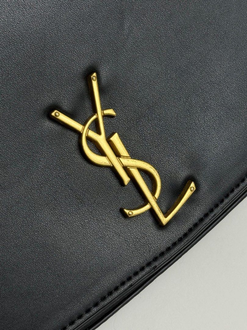 YSL Black Shoulder Bag (Category: Luxury Bags & Wallets) located in Manila. Submitted by eterna.luxe (Listing ID 1411421964, Image 3). Description: Black shoulder bag from Saint Laurent. Features a gold-tone YSL logo on the front. Includes a detachable shoulder strap and a zippered interior pocket. The interior is lined with black fabric and has a Saint Laurent logo embossed inside. The hardware is gold-toned, and the zipper pull is engraved with
