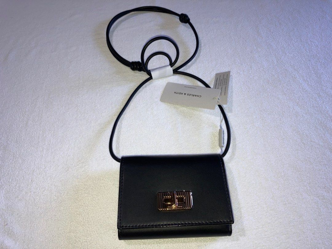 Charles & Keith - Edna Turn Lock Knotted Strap Wallet (Black) (Category: Wallets & Card holders) located in Bogo. Submitted by jantend (Listing ID 1411541258, Image 1). Description: 👜 Charles & Keith 2-in-1 Edna Turn-Lock Wallet & Mini Crossbody - Classic Black Elegance meets versatility. A chic accessory for day or night. ✨ Design & Features • Dual Style: Detachable strap converts wallet to mini crossbody • Premium Gold-Tone Turn-Lock: Luxury a
