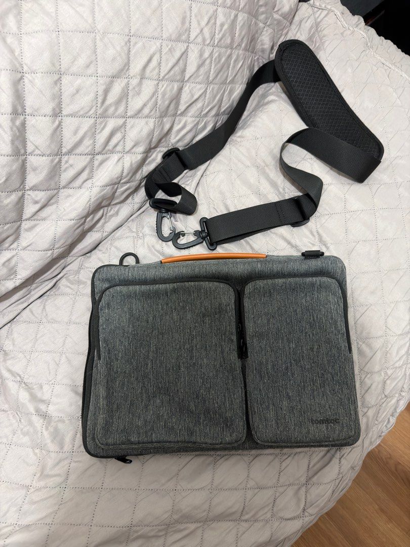 Tomtoc Defender Laptop Shoulder bag - 13 inch (Category: Laptop Bags & Sleeves) located in Pasig City. Submitted by vince.declutters (Listing ID 1411498722, Image 1). Description: Laptop bag features a padded interior and multiple compartments for storage. It includes a detachable shoulder strap for easy carrying. The bag has a handle with a brown leather accent. The bag has a zipper closure and a pocket on the front. - can fit a 13inch macbook -