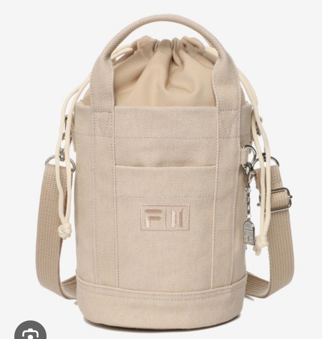 BTS X Fila Bucket Bag (Category: Cross-body Bags) located in Quezon City. Submitted by Cassidy (Listing ID 1411748467, Image 1). Description: - BTS Fila bucket bag - Beige canvas material - Drawstring closure - Top handle - Detachable shoulder strap - Interior pocket - BTS and Fila logo on front - Original Price 6000.