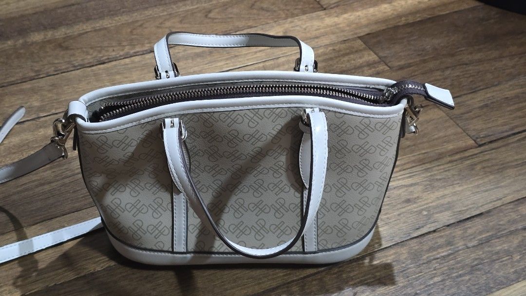 Hush Puppies patterned zippered shoulder bag in beige (Category: Shoulder Bags) located in Mandaluyong City. Submitted by joshlim (Listing ID 1411652673, Image 2). Description: Hush Puppies handbag features a beige and white color scheme with a patterned exterior. It includes a top zipper closure and a detachable shoulder strap. The interior has a brown lining and a small pocket. The bag has two handles and gold-colored hardware. The brand name i