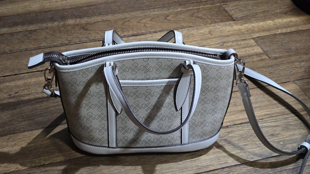 Hush Puppies patterned zippered shoulder bag in beige (Category: Shoulder Bags) located in Mandaluyong City. Submitted by joshlim (Listing ID 1411652673, Image 1). Description: Hush Puppies handbag features a beige and white color scheme with a patterned exterior. It includes a top zipper closure and a detachable shoulder strap. The interior has a brown lining and a small pocket. The bag has two handles and gold-colored hardware. The brand name i