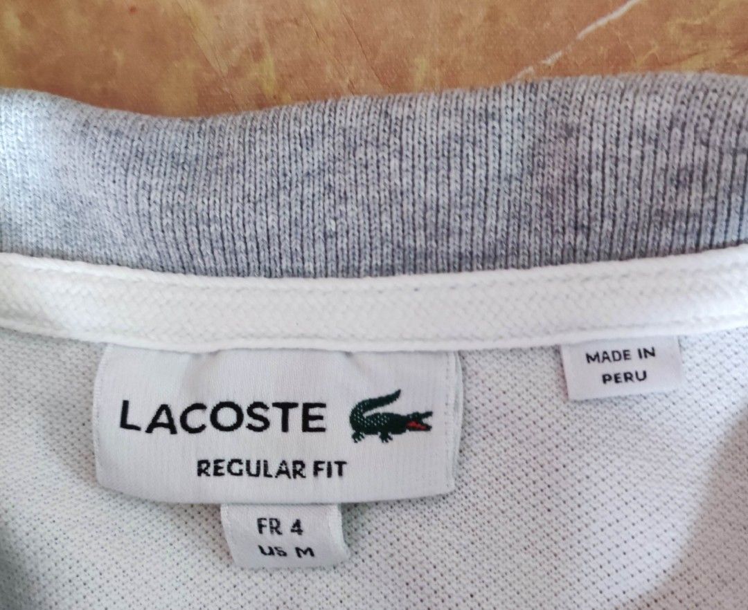 Lacoste Regular Fit Polo Shirt (Category: Tshirts & Polo Shirts ) located in Taguig. Submitted by lawrence_stuff (Listing ID 1411657447, Image 3). Description: - Authentic Lacoste polo shirt - Color: White with grey collar and cuffs - Features the iconic Lacoste crocodile logo - Made in Peru - Size: FR 4 / US M - Material: 100% cotton - Fit: Regular.