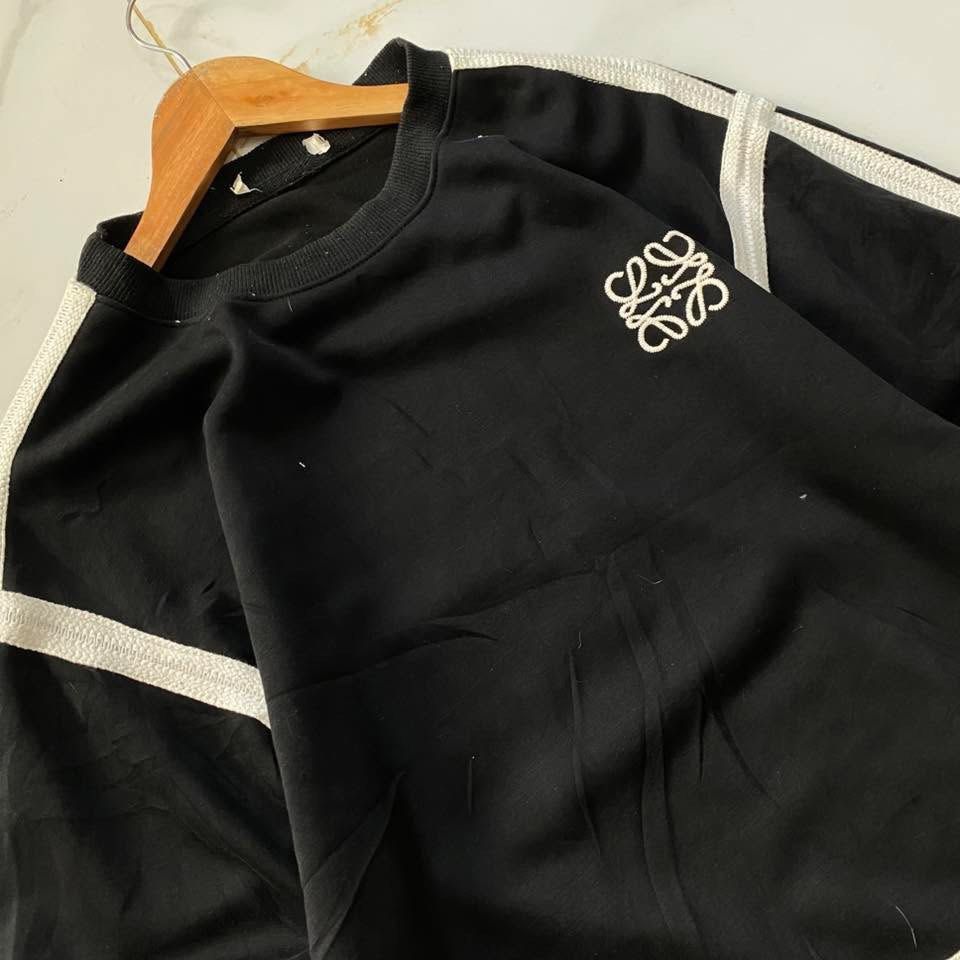 Loewe Black Sweatshirt with White Stripes (Category: Longsleeves) located in Manila. Submitted by ricszsthrift (Listing ID 1411720637, Image 2). Description: - Loewe sweatshirt with embroidered logo - White stripes on sleeves and hem - Crew neck design - Signs of wear and tear: - Faded stripes - Collar wear - Loose stitching in some areas 🌪️LOEWE (LONG SLEEVE) -DIMES: W-22.5 L-25.5 -9.5/10 CONDITION -9.5/10 COLOR RATE -DETAILS IS IN THE COMMENT 