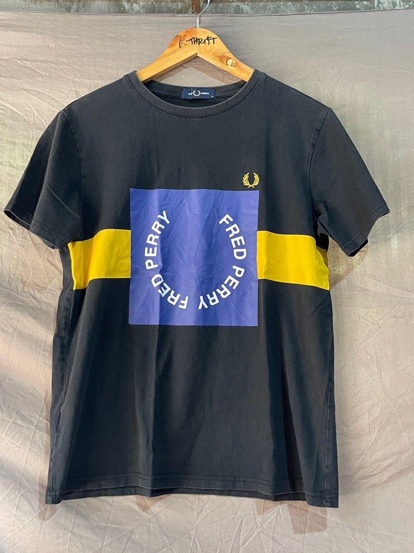 Fred Perry Graphic T-shirt (Category: Tshirts & Polo Shirts ) located in Cebu City. Submitted by retsiiiii (Listing ID 1411789278, Image 1). Description: - Black Fred Perry t-shirt - Yellow stripe across chest - Blue square with "FRED PERRY" print - Fred Perry logo on upper left chest - Short sleeves - Crew neck.