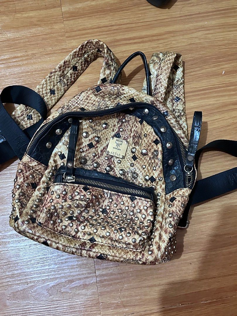 MCM Studded Backpack (Category: Luxury Bags & Wallets) located in Batangas. Submitted by prelovedby.juu (Listing ID 1411840357, Image 1). Description: - MCM backpack (authenticity not guaranteed: gifted item) - Snakeskin pattern with studded detailing - Front pocket with zipper closure - Top handle - Black interior with multiple compartments - Adjustable straps - MCM logo visible on front and back.