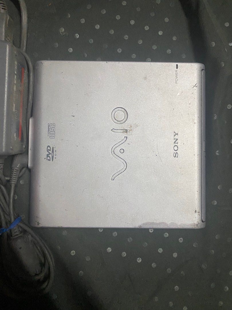 Sony VAIO PCGA-DVD1 DVD-ROM Drive (Category: Laptops & Notebooks) located in Manila. Submitted by olxph_540542159 (Listing ID 1411794097, Image 2). Description: - Sony VAIO PCGA-DVD1 DVD-ROM Drive - Includes the drive and power adapter - Features a stylish silver finish - VAIO logo is prominently displayed - Portable DVD-ROM drive.
