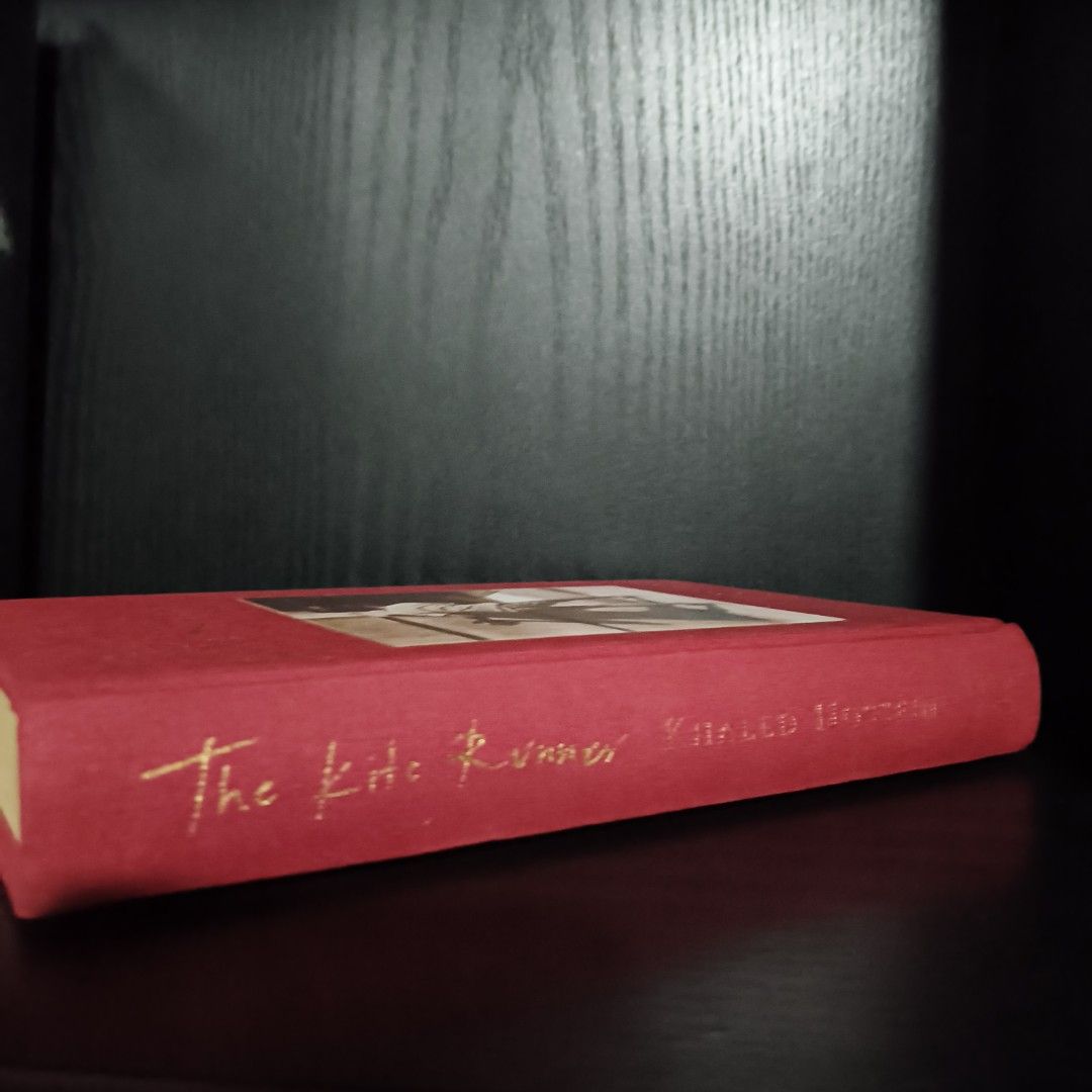 the kite runner (hardcover) khaled hosseini (Category: Storybooks) located in Rosales. Submitted by leejonli2 (Listing ID 1411924918, Image 3). Description: - "The Kite Runner" by Khaled Hosseini - Red cover with gold lettering - Features a boy on the cover - Clean pages and sturdy binding - A compelling and engaging story.