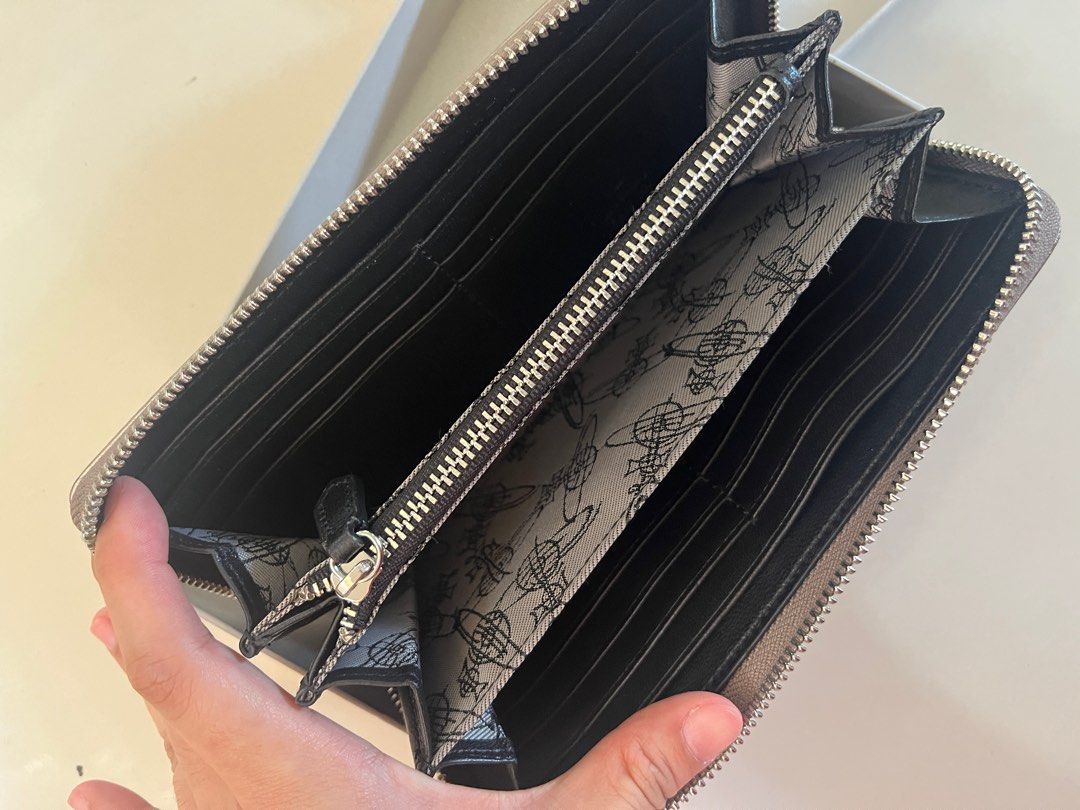 AUTHENTIC Vivienne Westwood Zip Around Wallet (Category: Wallets & Card holders) located in Quezon City. Submitted by shopacc_00 (Listing ID 1411808801, Image 3). Description: - Authentic Vivienne Westwood wallet - Zip-around style - Silver-tone exterior - Features iconic orb emblem - Multiple compartments for cards and cash - Comes with original box - Box shows wear and tear.