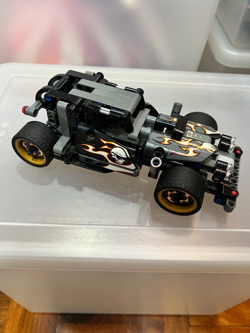 Lego Technic Hot Rod Car (Category: Lego & Building Sets) located in Pasig City. Submitted by theclosetcasemanila (Listing ID 1412030379, Image 2). Description: - Lego Technic Hot Rod - Hot rod design with flame and skull decals - Black tires with gold rims - Primarily black and gray color scheme - Detailed model with visible mechanical components.