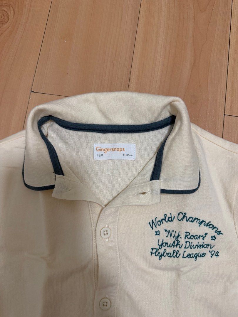 Gingersnaps World Champions Shirt 18M (Category: Babies & Kids Fashion) located in Manila. Submitted by ziaaa012 (Listing ID 1412293623, Image 2). Description: - Brand: Gingersnaps - Size: 18 months - Color: Cream - Design: High collar, short sleeves with dark blue trim, button-up front, and ribbed hem - Embroidery: "World Champions N.Y. Roars Youth Division Flyball League '94".