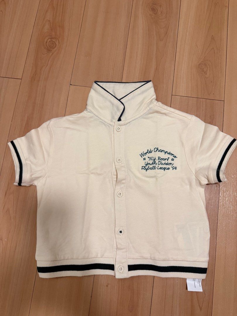 Gingersnaps World Champions Shirt 18M (Category: Babies & Kids Fashion) located in Manila. Submitted by ziaaa012 (Listing ID 1412293623, Image 1). Description: - Brand: Gingersnaps - Size: 18 months - Color: Cream - Design: High collar, short sleeves with dark blue trim, button-up front, and ribbed hem - Embroidery: "World Champions N.Y. Roars Youth Division Flyball League '94".