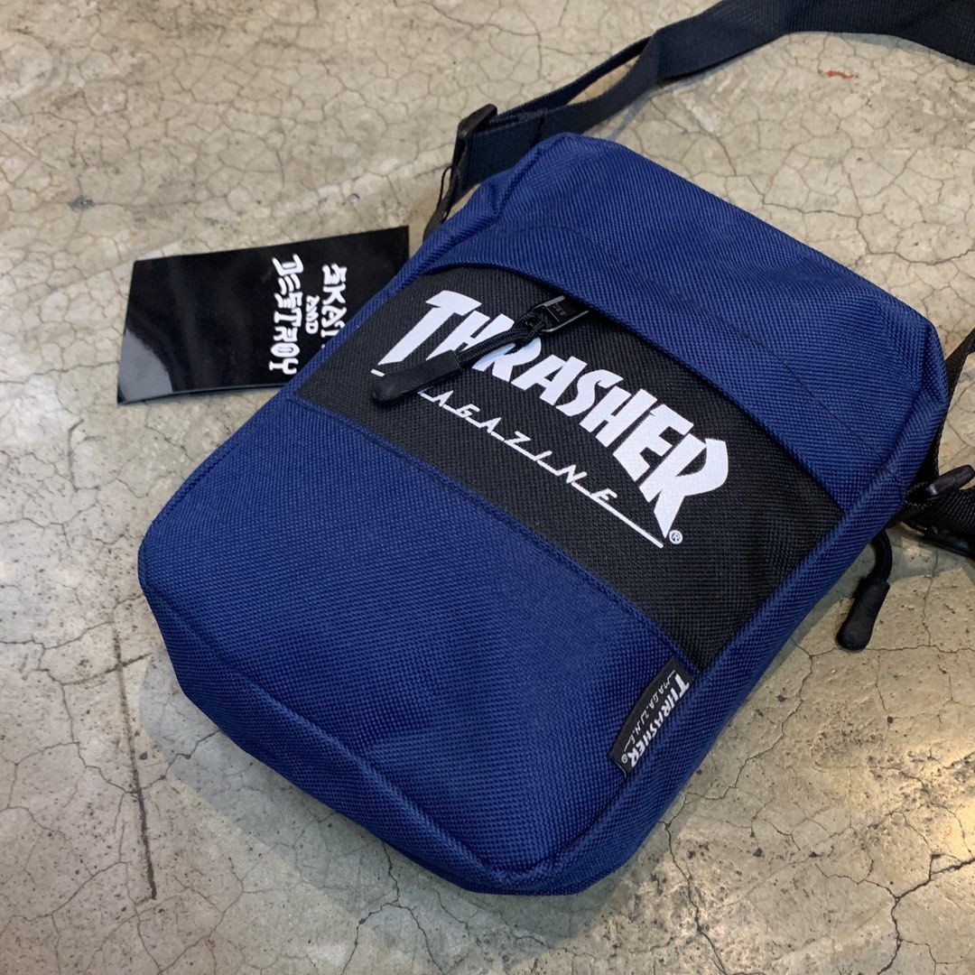 Thrasher Magazine Crossbody Bag (Category: Sling Bags) located in Pasig City. Submitted by paymelikelandlord (Listing ID 1412324680, Image 2). Description: Thrasher Magazine crossbody bag features a navy blue body with the brand's logo prominently displayed. It has a black strap and a zippered main compartment. The bag includes a tag that says "Skate and Destroy"..