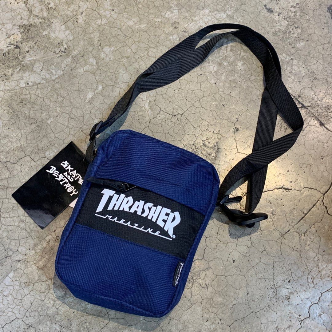 Thrasher Magazine Crossbody Bag (Category: Sling Bags) located in Pasig City. Submitted by paymelikelandlord (Listing ID 1412324680, Image 3). Description: Thrasher Magazine crossbody bag features a navy blue body with the brand's logo prominently displayed. It has a black strap and a zippered main compartment. The bag includes a tag that says "Skate and Destroy"..