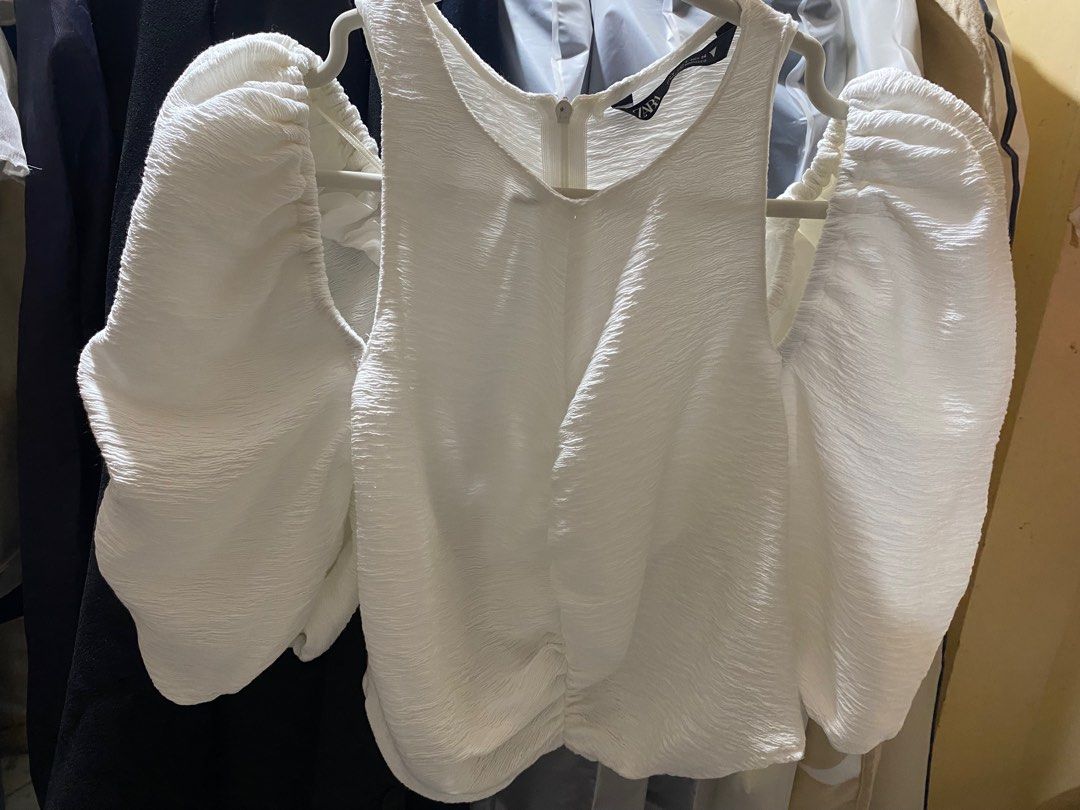 Zara White Off-Shoulder Top (Category: Blouses) located in Pasay City. Submitted by _jkching (Listing ID 1412270499, Image 2). Description: - Zara off-shoulder top - White, textured fabric - Size: S - Features: - Puff sleeves - Gathered front detail - Zipper closure at the back - Made in Morocco.