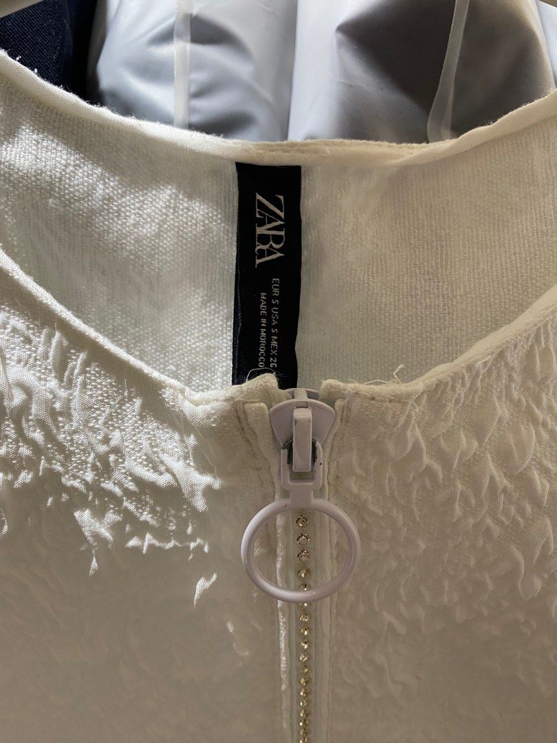 Zara White Textured Top with Zipper (Category: Blouses) located in Pasay City. Submitted by _jkching (Listing ID 1412272522, Image 2). Description: - Zara white textured top - Size S - Round neckline - Short, puffy sleeves - Front zipper closure - Unique textured fabric - Made in Morocco.