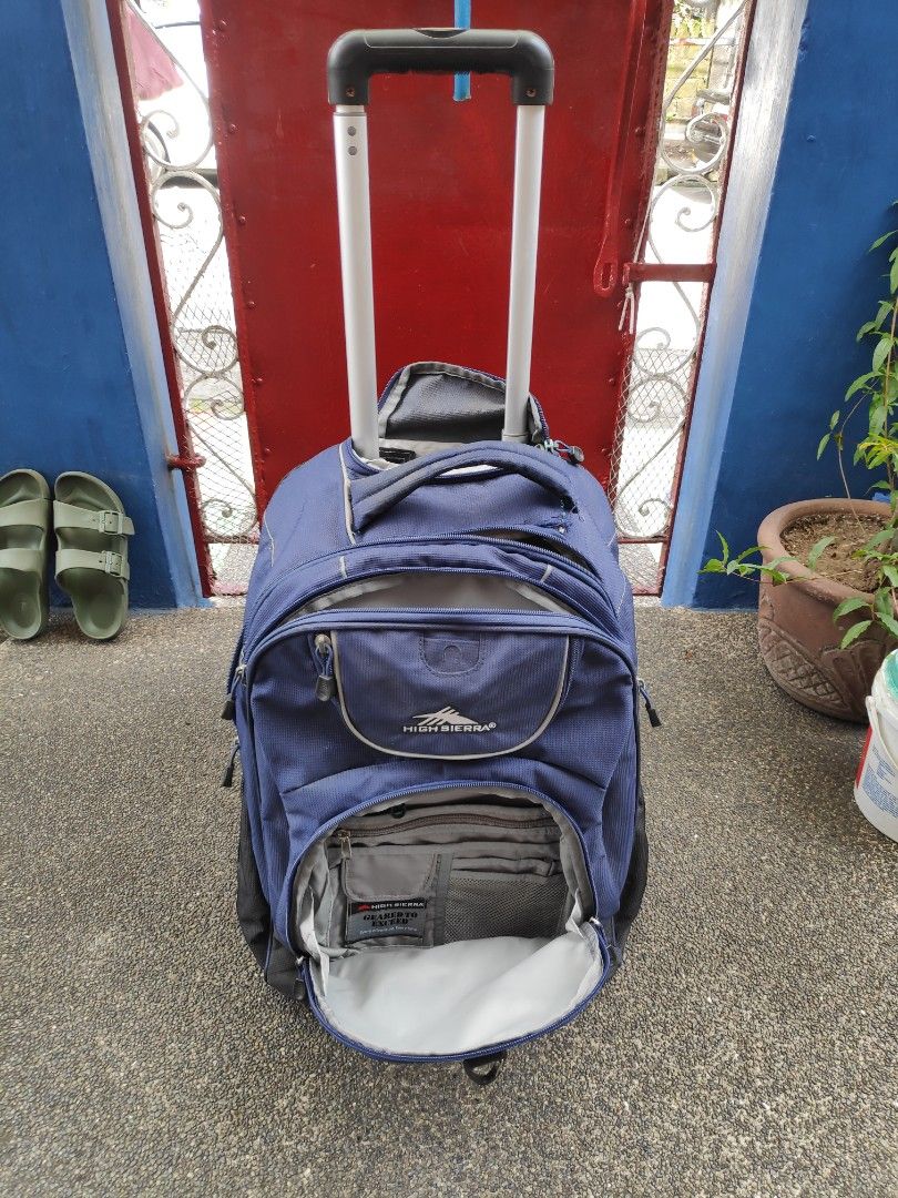 High Sierra Rolling Backpack (Category: Backpacks) located in Quezon City. Submitted by j.c.declutter (Listing ID 1412361212, Image 2). Description: - High Sierra rolling backpack - Navy blue color - Multiple compartments and pockets for organization - Retractable handle and wheels for easy rolling - Padded back panel for comfort - Shoulder straps for carrying - Functional zippers - Original Price 8000.