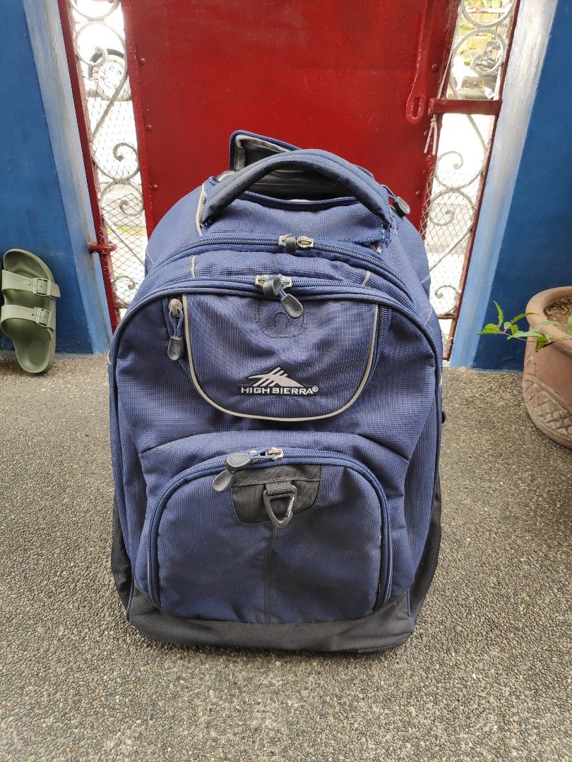 High Sierra Rolling Backpack (Category: Backpacks) located in Quezon City. Submitted by j.c.declutter (Listing ID 1412361212, Image 1). Description: - High Sierra rolling backpack - Navy blue color - Multiple compartments and pockets for organization - Retractable handle and wheels for easy rolling - Padded back panel for comfort - Shoulder straps for carrying - Functional zippers - Original Price 8000.