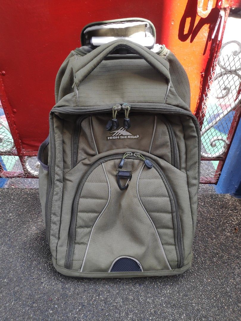 High Sierra Wheeled Backpack (Category: Backpacks) located in Quezon City. Submitted by j.c.declutter (Listing ID 1412358109, Image 1). Description: - High Sierra rolling backpack - Durable construction - Multiple compartments for organization - Padded laptop sleeve - Retractable handle for easy rolling - Adjustable shoulder straps - Cushioned back panel for comfort - Green exterior with multiple pockets - Original Price 4000.