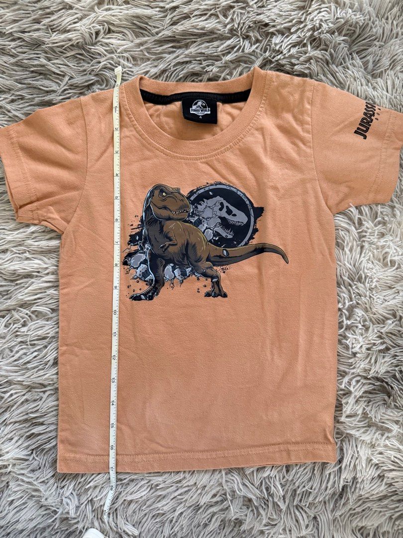 Jurassic World T-shirt (Category: Tshirts & Polo Shirts ) located in Muntinlupa City. Submitted by caistuff (Listing ID 1412390221, Image 2). Description: LAST PRICE POSTED ALREADY. - Jurassic World t-shirt for kids - Features a dinosaur graphic on the front - Jurassic World logo on the sleeve - Short-sleeved - Round neckline - Light brown color Dimes: - Length: 17 in - Width: 12 in.