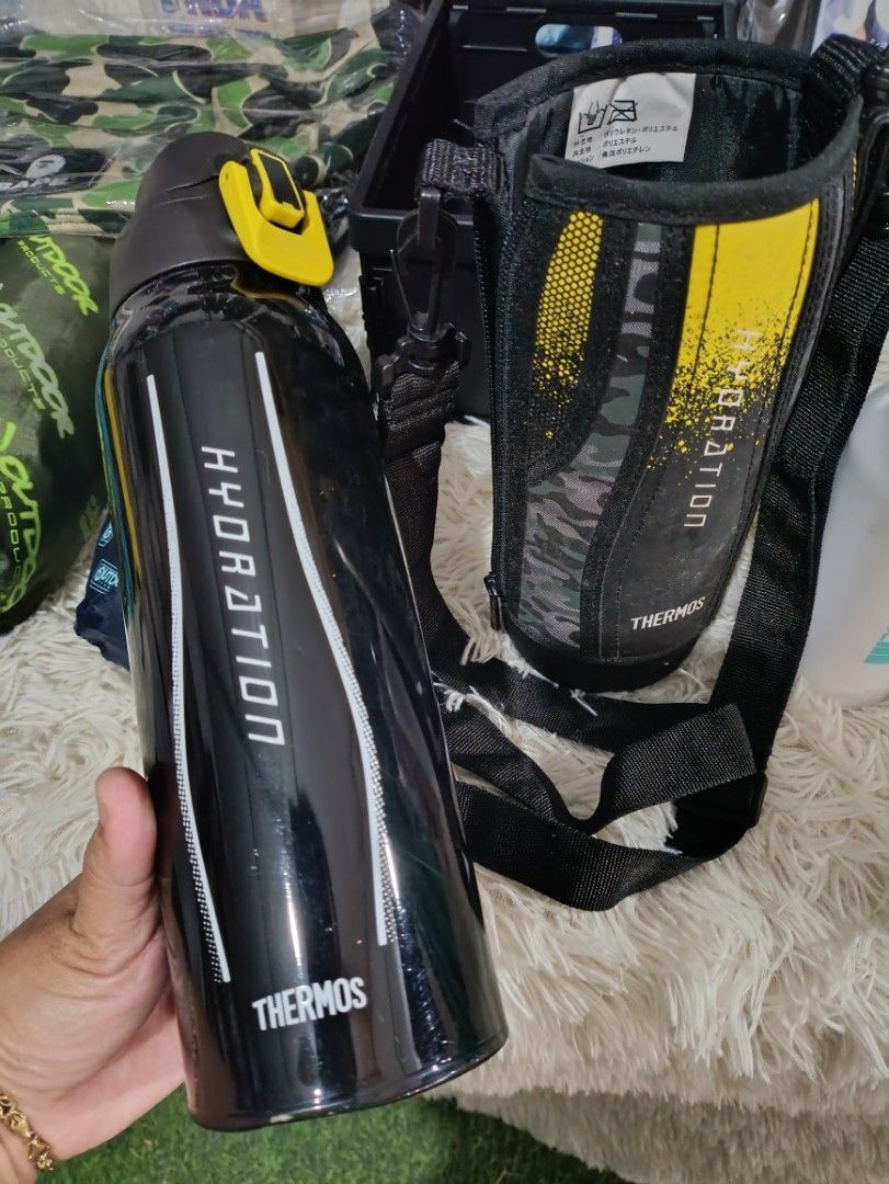 Thermos Hydration Water Bottle with Pouch (Category: Water Bottles & Tumblers) located in Bacoor. Submitted by MommahAnnaOnlineShop (Listing ID 1412514751, Image 3). Description: Thermos water bottle comes with a matching pouch. The bottle is black with the word "HYDRATION" printed on it. The bottle has a screw-on lid with a blue interior. The pouch has a shoulder strap and a yellow and black design. The bottom of the bottle has a label with deta