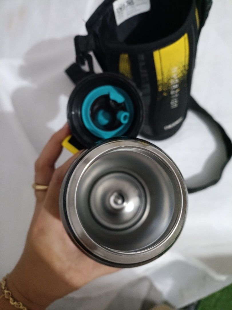 Thermos Hydration Water Bottle with Pouch (Category: Water Bottles & Tumblers) located in Bacoor. Submitted by MommahAnnaOnlineShop (Listing ID 1412514751, Image 2). Description: Thermos water bottle comes with a matching pouch. The bottle is black with the word "HYDRATION" printed on it. The bottle has a screw-on lid with a blue interior. The pouch has a shoulder strap and a yellow and black design. The bottom of the bottle has a label with deta