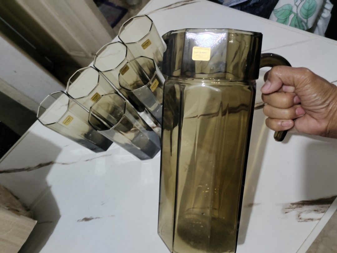 Vintage Pitcher and Glass Set (Category: Pitchers & Dispensers) located in Quezon City. Submitted by 09275375503 (Listing ID 1412486290, Image 3). Description: Luminarc pitchel Set includes a pitcher and six glasses. The glasses have a unique geometric design. The set is a smoky brown color. The pitcher has a handle for easy pouring. Each glass has a sticker on it. This set is perfect for serving drinks at home..