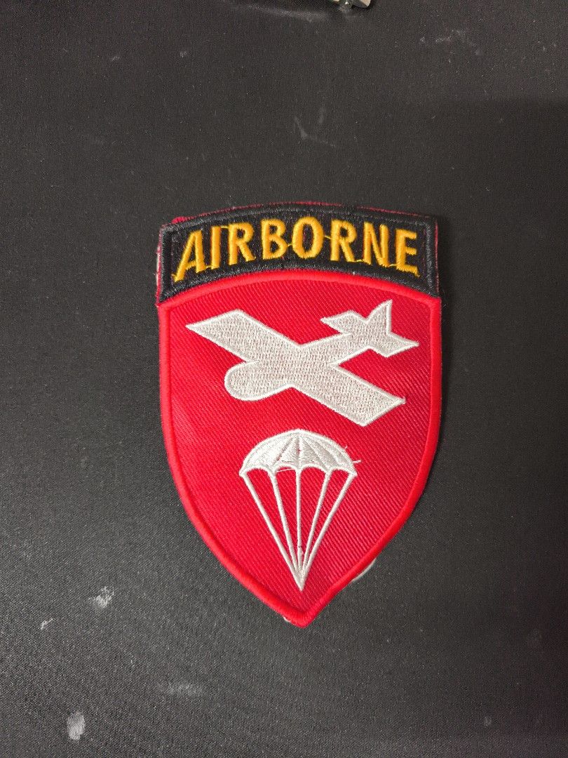 Airborne Patch (Category: Coats, Jackets and Outerwear) located in Gelang Patah. Submitted by 126bundle (Listing ID 1407570374, Image 1). Description: Airborne patch featuring a red shield with a white airplane and parachute design. The word "AIRBORNE" is embroidered in yellow on a black background at the top..