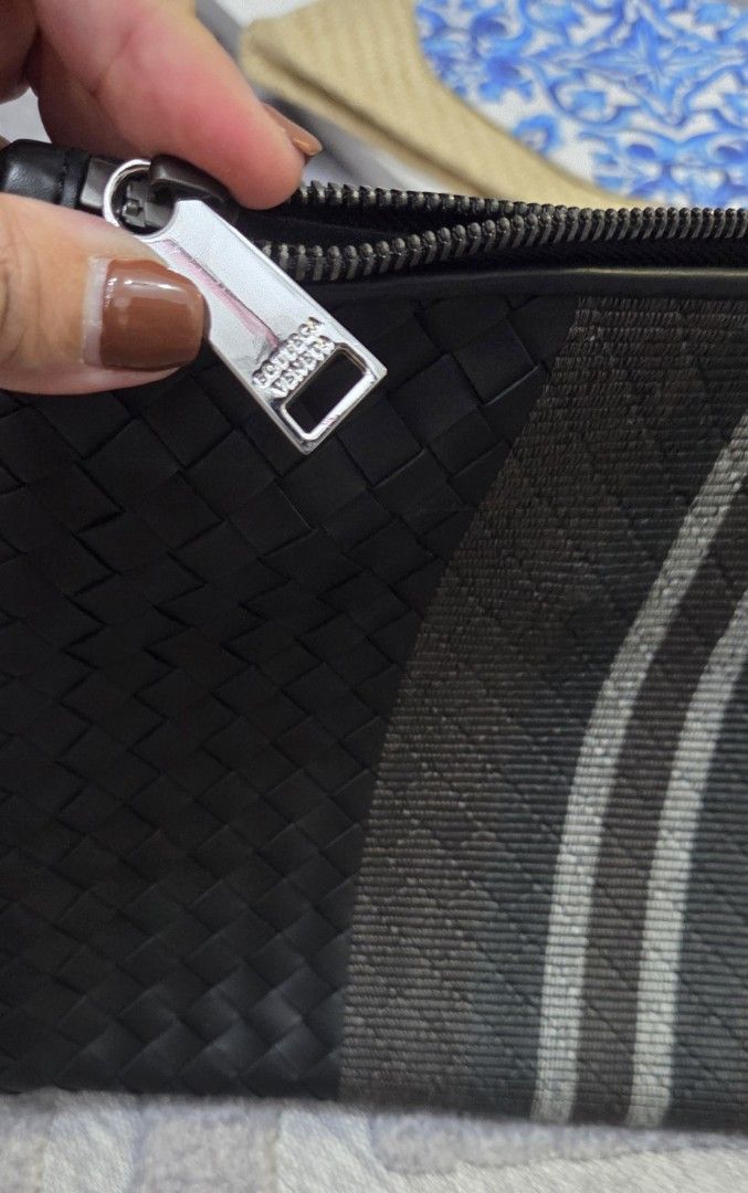 Bottega Veneta Woven Authentic Clutch (Category: Luxury Bags & Wallets) located in Manila. Submitted by sterling_grace (Listing ID 1407593564, Image 3). Description: - Black woven leather clutch - Central stripe design - Wrist strap included - Secure zipper closure - Features Bottega Veneta logo on zipper pull - Rectangular shape.
