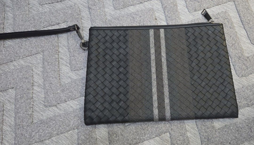 Bottega Veneta Woven Authentic Clutch (Category: Luxury Bags & Wallets) located in Manila. Submitted by sterling_grace (Listing ID 1407593564, Image 2). Description: - Black woven leather clutch - Central stripe design - Wrist strap included - Secure zipper closure - Features Bottega Veneta logo on zipper pull - Rectangular shape.