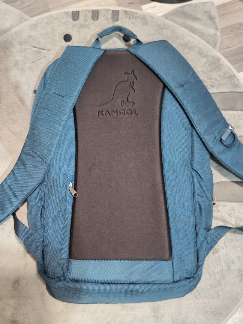 Kangol Backpack (Category: Backpacks) located in Davao. Submitted by deethriftshop.co (Listing ID 1407747896, Image 2). Description: Kangol backpack features a teal exterior with multiple compartments. It has a front pocket with a zipper, a main compartment with a laptop sleeve, and has a number of pockets inside. The back of the backpack has a padded panel with the Kangol logo and also has a secret pocket. The interior lining is orange. There is
