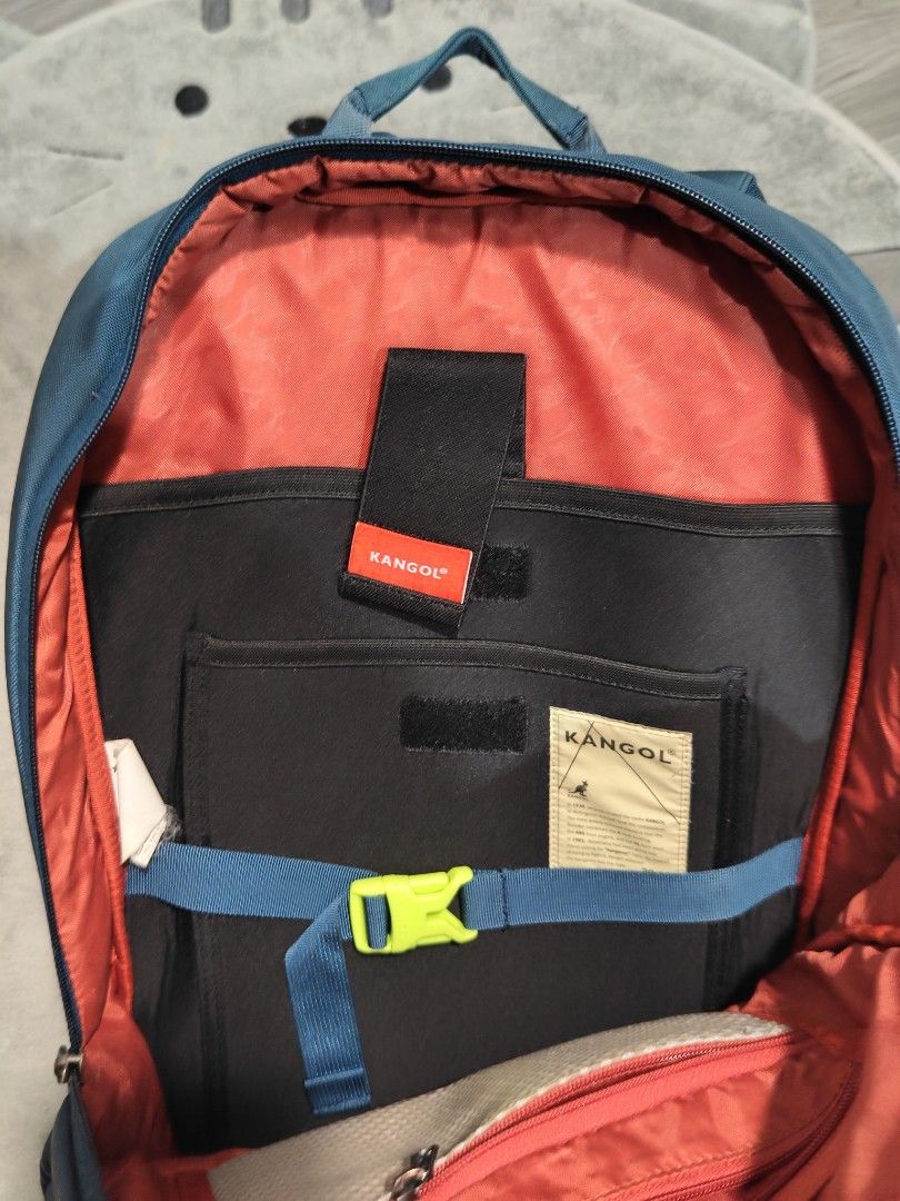 Kangol Backpack (Category: Backpacks) located in Davao. Submitted by deethriftshop.co (Listing ID 1407747896, Image 3). Description: Kangol backpack features a teal exterior with multiple compartments. It has a front pocket with a zipper, a main compartment with a laptop sleeve, and has a number of pockets inside. The back of the backpack has a padded panel with the Kangol logo and also has a secret pocket. The interior lining is orange. There is