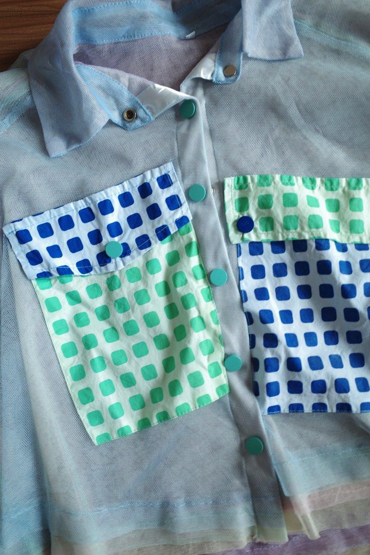 Sheer Cropped Top with Pocket Details (Category: Blouses) located in Makati City. Submitted by bluelocker (Listing ID 1407653392, Image 2). Description: - Sheer cropped top - Collared neckline - Short sleeves - Button-down closure - Two front pockets with blue and green square pattern - Layered hem design - Primarily light blue color with pastel accents.