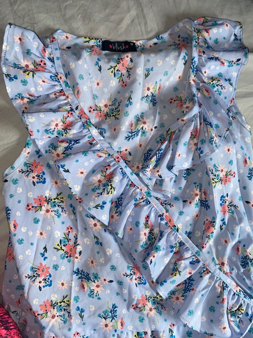 Blush Floral Ruffle Dress (Category: Babies & Kids Fashion) located in Manila. Submitted by serabuy (Listing ID 1412575468, Image 2). Description: - Floral print dress - Light blue base - Ruffle details on neckline and sleeves - Wrap-style design - Includes waist tie - Sleeveless - Brand tag visible.