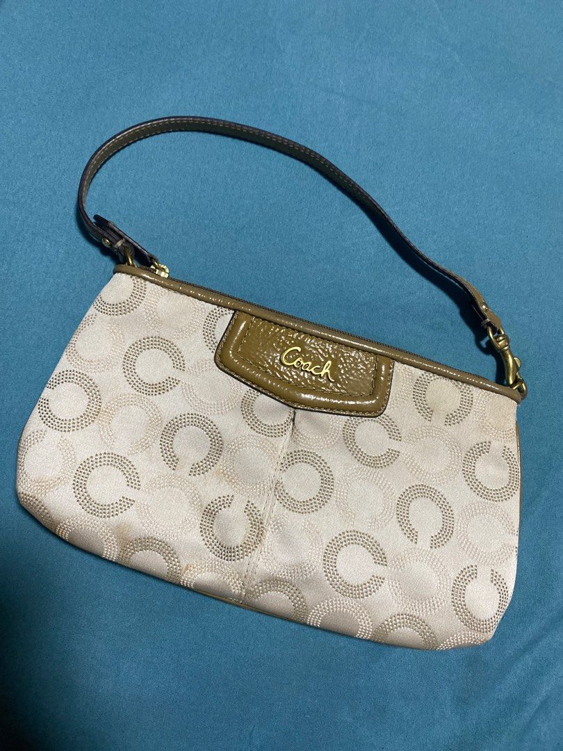 Coach Signature Clutch (Category: Luxury Bags & Wallets) located in Quezon City. Submitted by Daichy (Listing ID 1412568846, Image 1). Description: - Coach signature clutch - Includes wrist strap - Light-colored fabric with repeating circle pattern - Dark brown trim and strap - Coach logo on front - Gold-colored clasp and hardware.