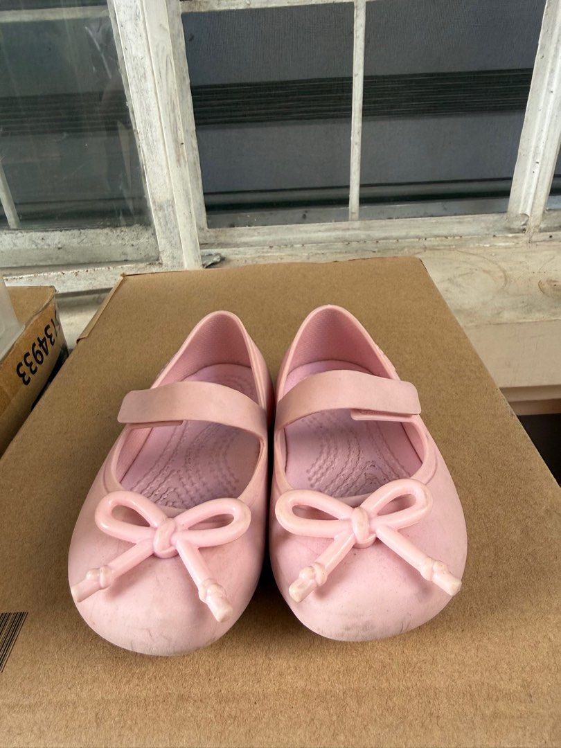 Crocs Kids Ballet Flats - Pink (Category: Babies & Kids Fashion) located in Pasig City. Submitted by 5ftunder (Listing ID 1412533099, Image 1). Description: - Pink Crocs ballet flats for kids - Features a strap closure and bow detail - Textured sole for grip - Crocs logo visible - Made of a rubber-like material.
