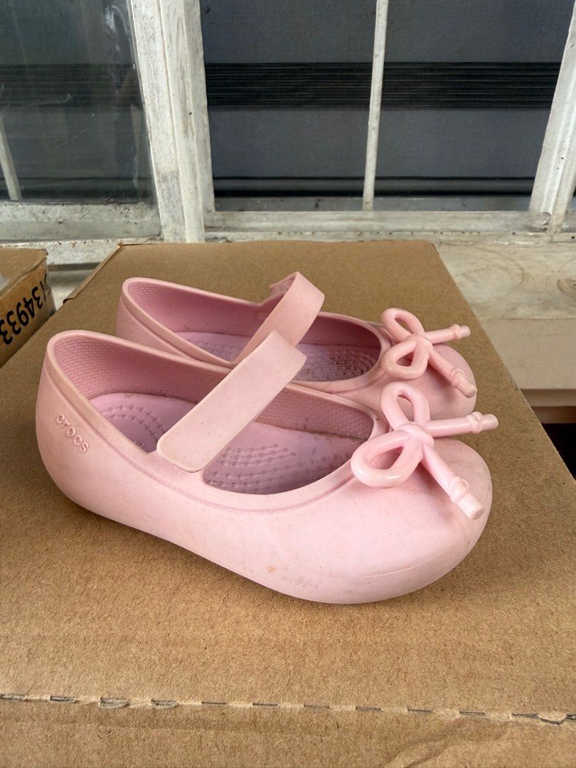 Crocs Kids Ballet Flats - Pink (Category: Babies & Kids Fashion) located in Pasig City. Submitted by 5ftunder (Listing ID 1412533099, Image 3). Description: - Pink Crocs ballet flats for kids - Features a strap closure and bow detail - Textured sole for grip - Crocs logo visible - Made of a rubber-like material.