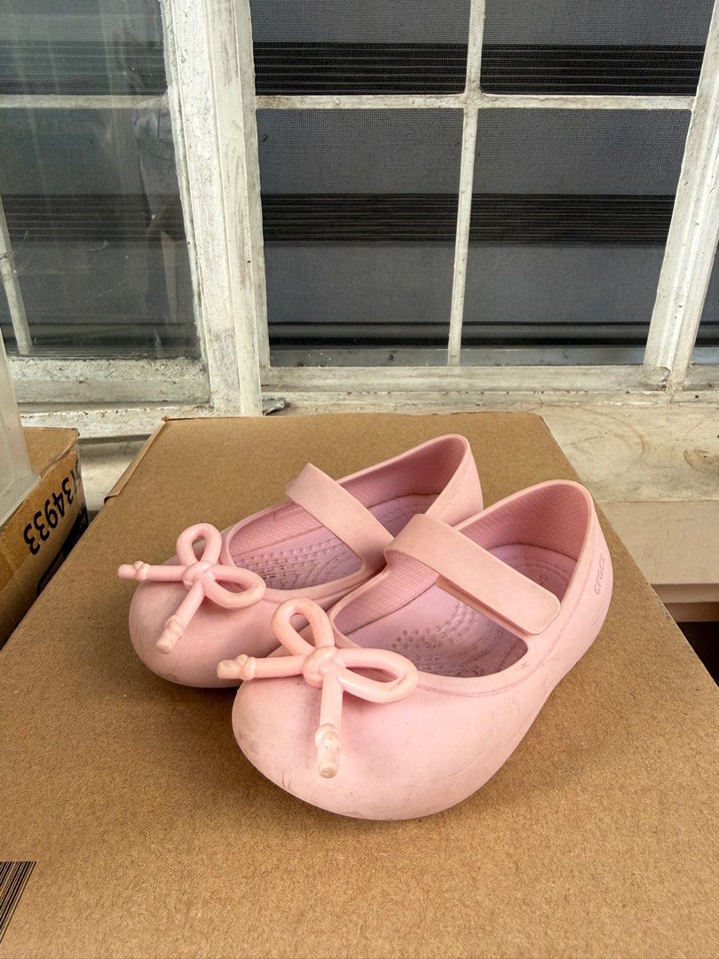 Crocs Kids Ballet Flats - Pink (Category: Babies & Kids Fashion) located in Pasig City. Submitted by 5ftunder (Listing ID 1412533099, Image 2). Description: - Pink Crocs ballet flats for kids - Features a strap closure and bow detail - Textured sole for grip - Crocs logo visible - Made of a rubber-like material.
