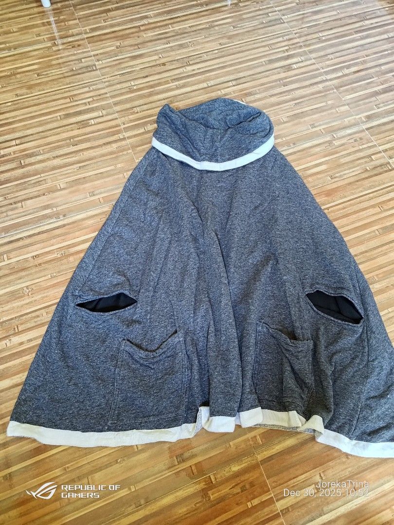 Grey Poncho with pockets (Category: Coats, Jackets and Outerwear) located in San Fernando. Submitted by masterambrose13 (Listing ID 1412542864, Image 1). Description: a hooded poncho or cocoon hoodie, a loose-fitting, casual garment typically made of a soft, possibly jersey or fleece, material. It is grey with white piping trim along the hood/neckline, hem, and pocket openings. Product Information Type: Hooded poncho, cocoon hoodie, or sweater ve