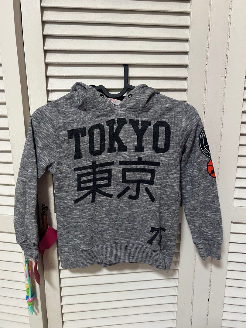 H&M Tokyo Hoodie (Category: Babies & Kids Fashion) located in Manila. Submitted by treenitea (Listing ID 1412568528, Image 1). Description: Gray hoodie with "TOKYO" printed on the front. Features Japanese characters below the word "TOKYO". Has a small patch on the left sleeve. The tag indicates it is size EUR 110/116, US 4-6Y, CA/AA CN 120/60, and MX 110/116 AUS 5-6..