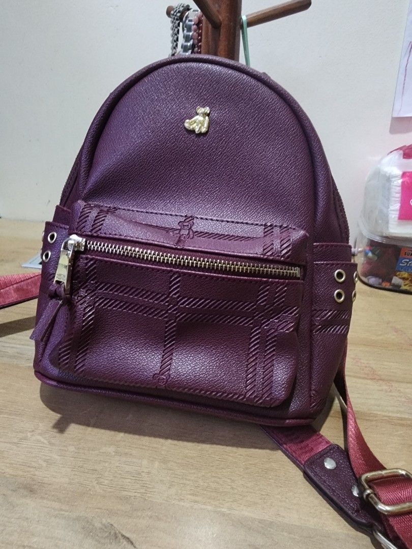 Teenie Weenie Mini Backpack - Burgundy (Category: Backpacks) located in Quezon City. Submitted by zarheign (Listing ID 1412622045, Image 1). Description: Mini backpack features a stylish burgundy color and a compact design. It has a front pocket with a zipper and a main compartment with a patterned lining. The backpack includes adjustable straps and a top handle. Brand hologram in the inside lining. It has a gold-colored logo on the front..