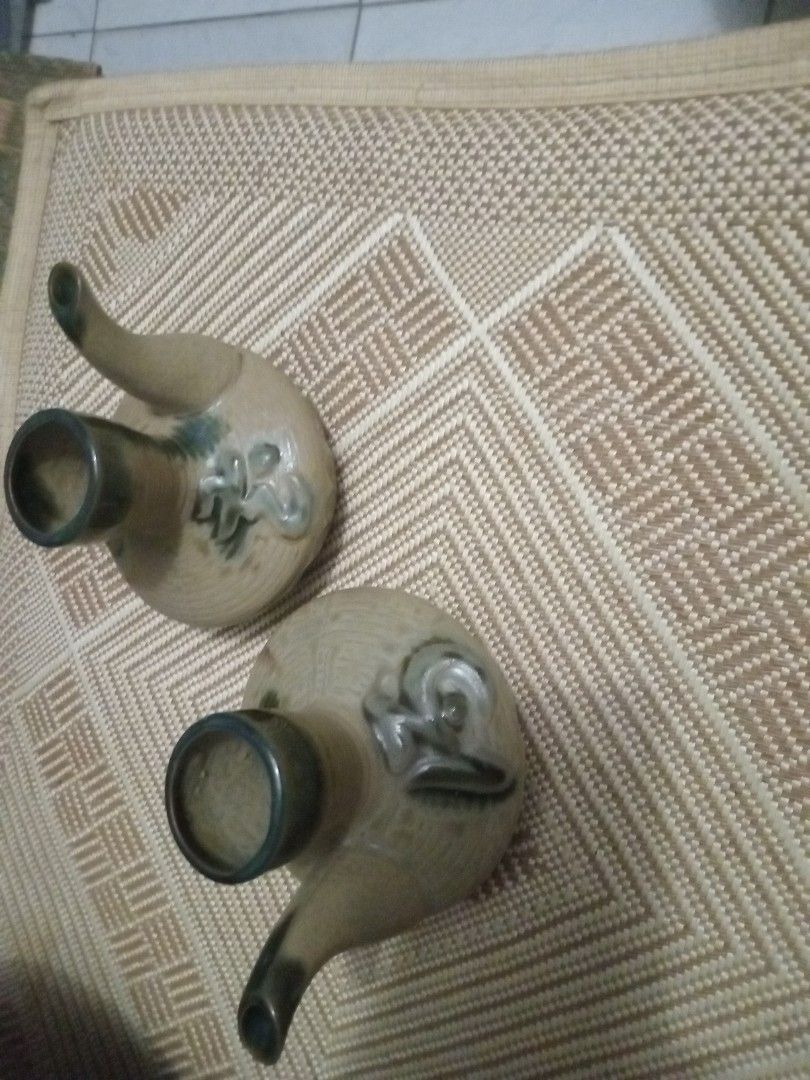 Vintage Japanese Sake Pourers (Category: Dinnerware & Cutlery) located in Manila. Submitted by padillahe35291 (Listing ID 1412621607, Image 1). Description: Set of two vintage Japanese sake pourers. They have a unique design with a spout and a wide opening. The pourers feature a decorative floral design. The color is a mix of beige and green. These pourers are perfect for serving sake in style..