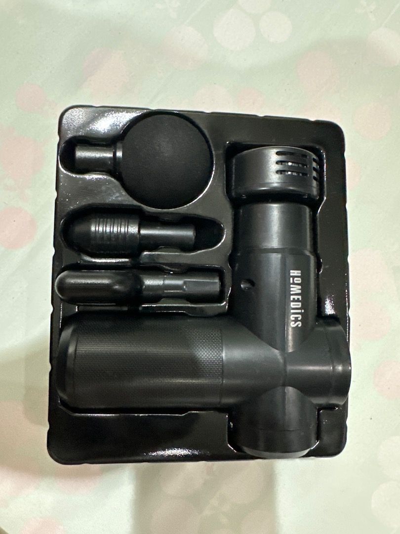 HoMedics Percussion Massage Gun (Category: Massage Devices) located in San Pedro. Submitted by shein2010 (Listing ID 1407859828, Image 1). Description: HoMedics massage gun comes with multiple attachments for targeted muscle relief. The attachments include a round head, a bullet head, and a flat head. The massage gun itself has a textured grip and the HoMedics logo is visible..