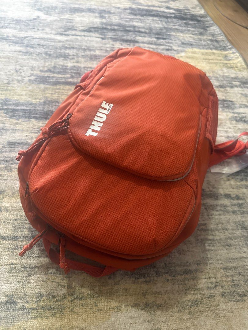 Thule Backpack (Category: Backpacks) located in Gombak. Submitted by sharking86 (Listing ID 1407760838, Image 2). Description: - Vibrant orange Thule backpack - Multiple compartments for storage - Padded back for comfort - Adjustable straps for a custom fit - Includes Thule tag - Stylish and practical design.